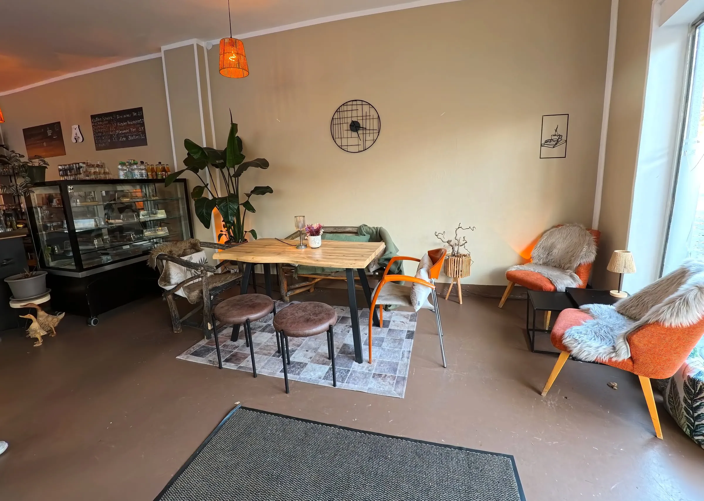 Eine Ecke am Fenster mit orangen Sesseln, Fellen und einem Holztisch