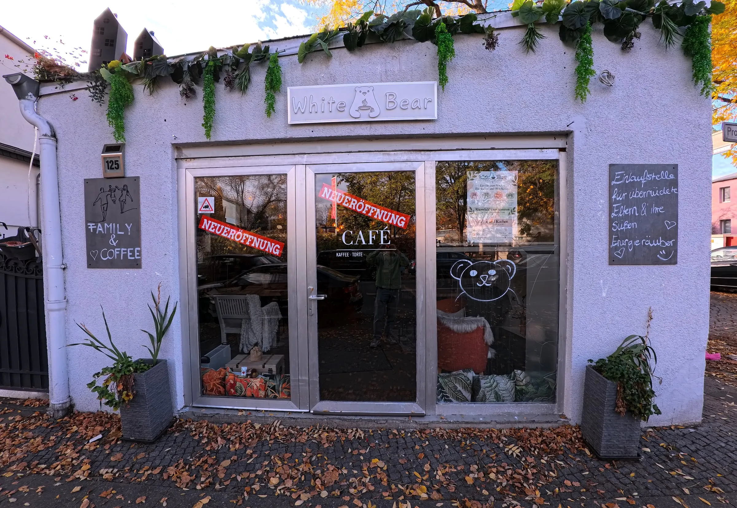 Das White Bear Café von außen: weißes Haus mit Glastür, Bär-Schild und Kreidetafeln