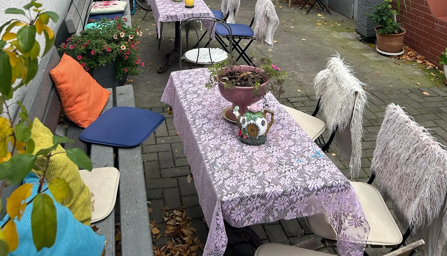 Der Innenhof mit Tischen, Spitzendecken, Bänken und Blumen